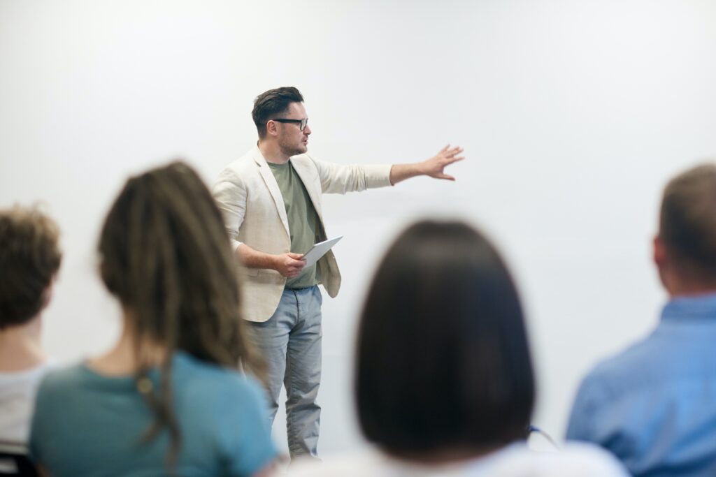 A man stands in front of his coworkers and explains something to them.