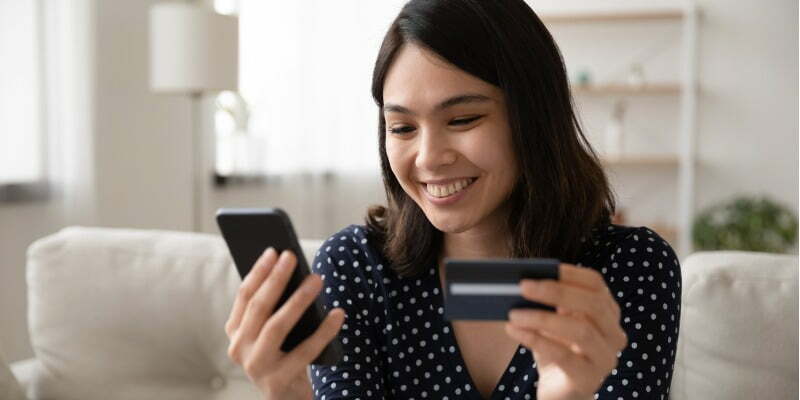a smiling woman holding her phone and credit card